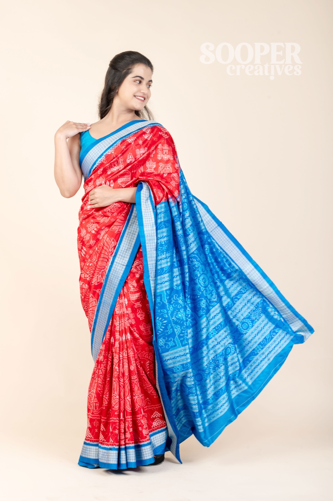Full-length fashion model posing in a red and blue saree on a clean Noida studio set