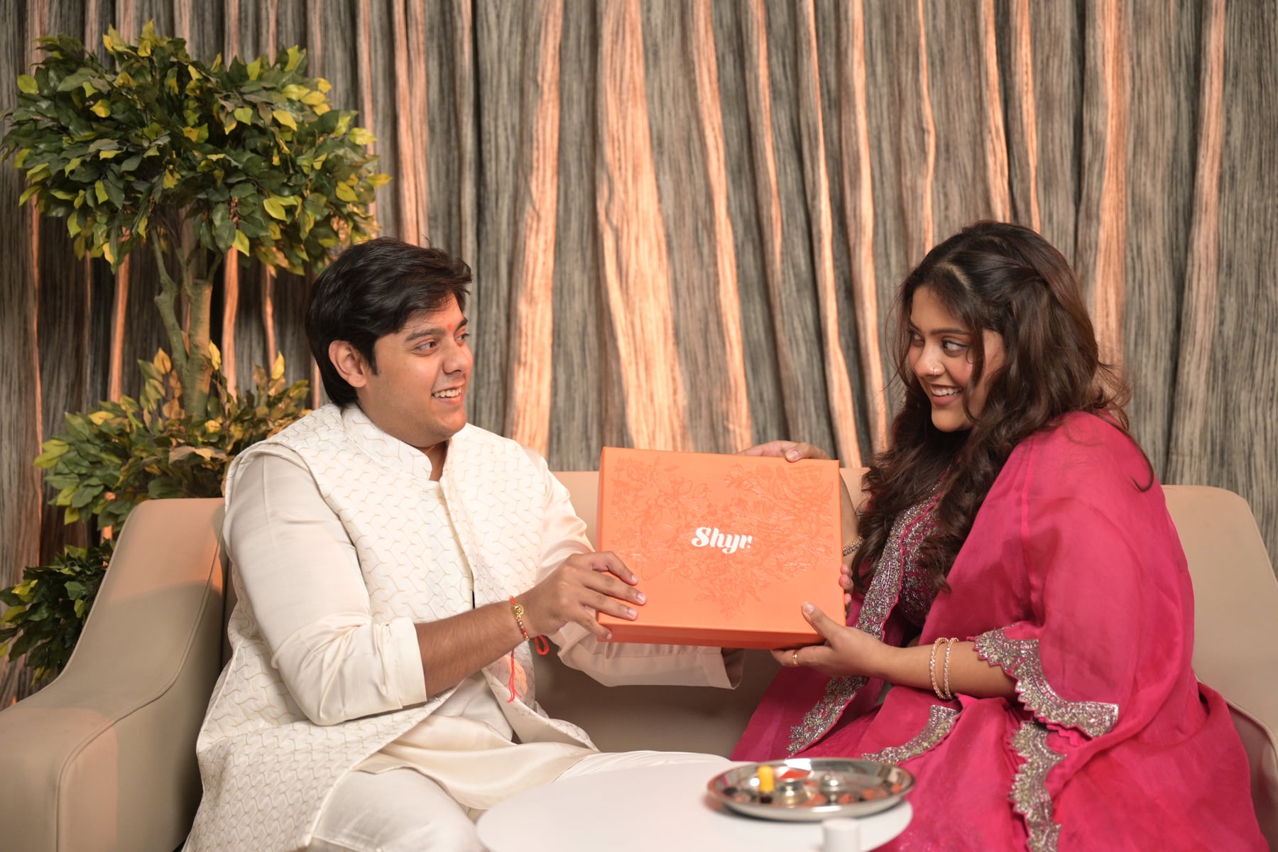 Brother and sister seated with a Rakhi gift box on a festive lifestyle set