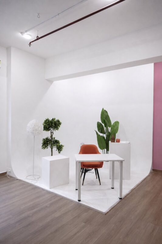 Wide white cyclorama inside Sooper Studios with a chair table plants and plinths in Noida