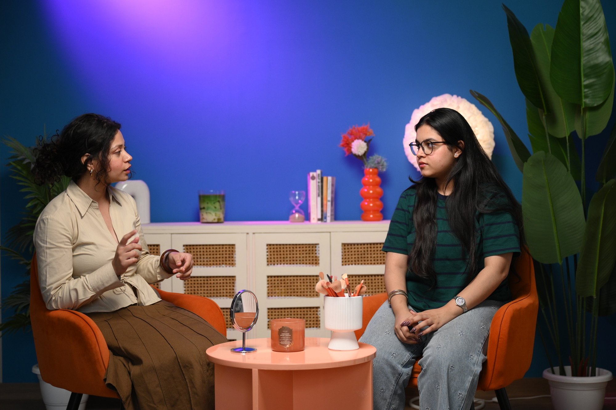 Two people seated in conversation on a controlled blue video set at Sooper Studios in Noida