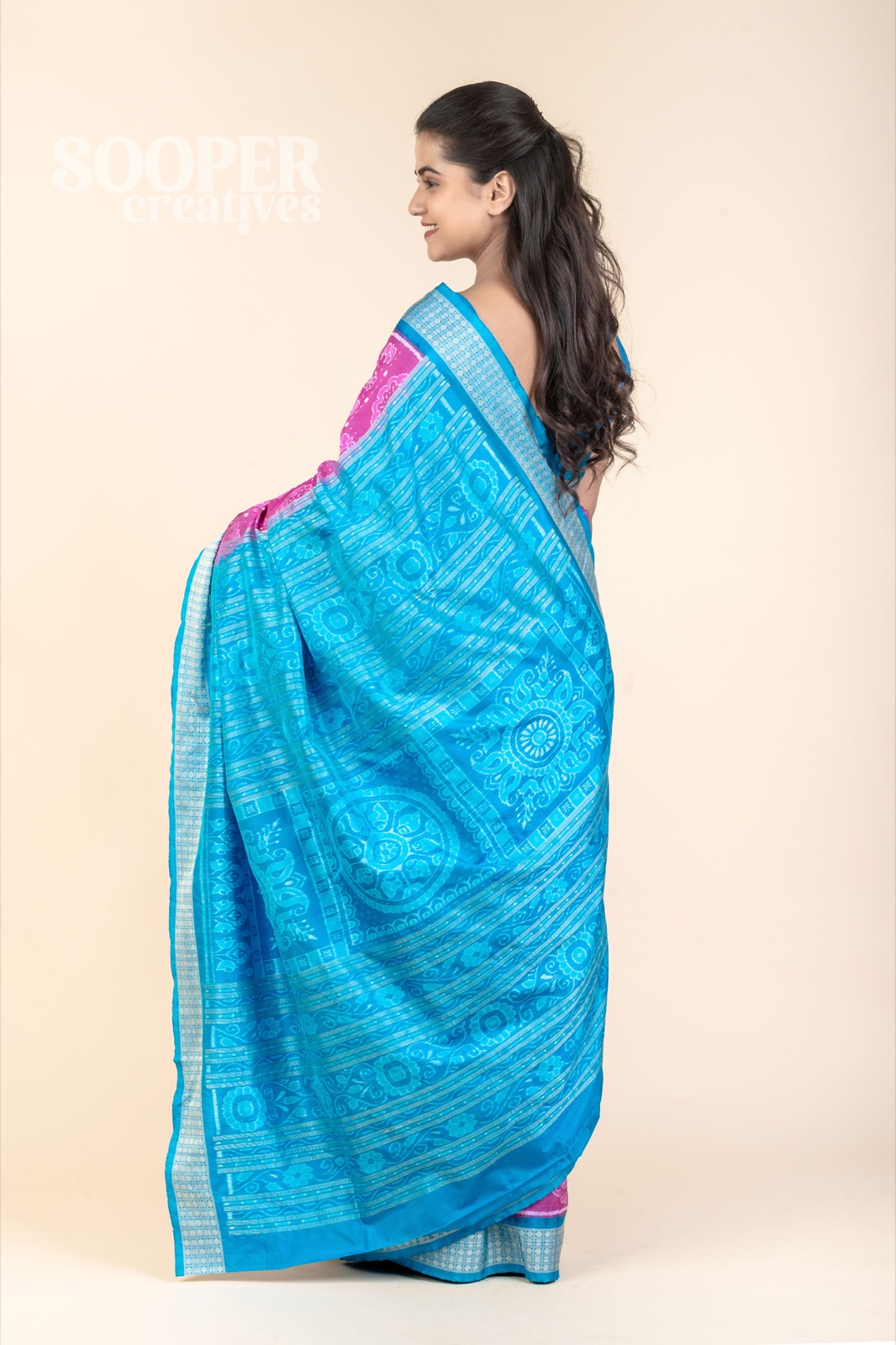 Fashion model displaying a bright blue and pink saree on a controlled neutral studio background