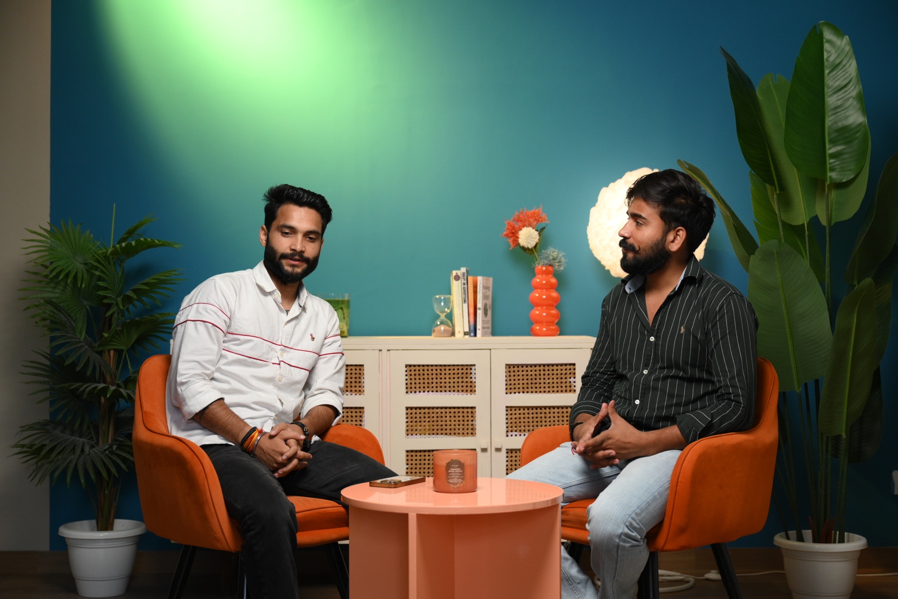 Two men recording a conversation on a teal video podcast set at Sooper Studios in Noida