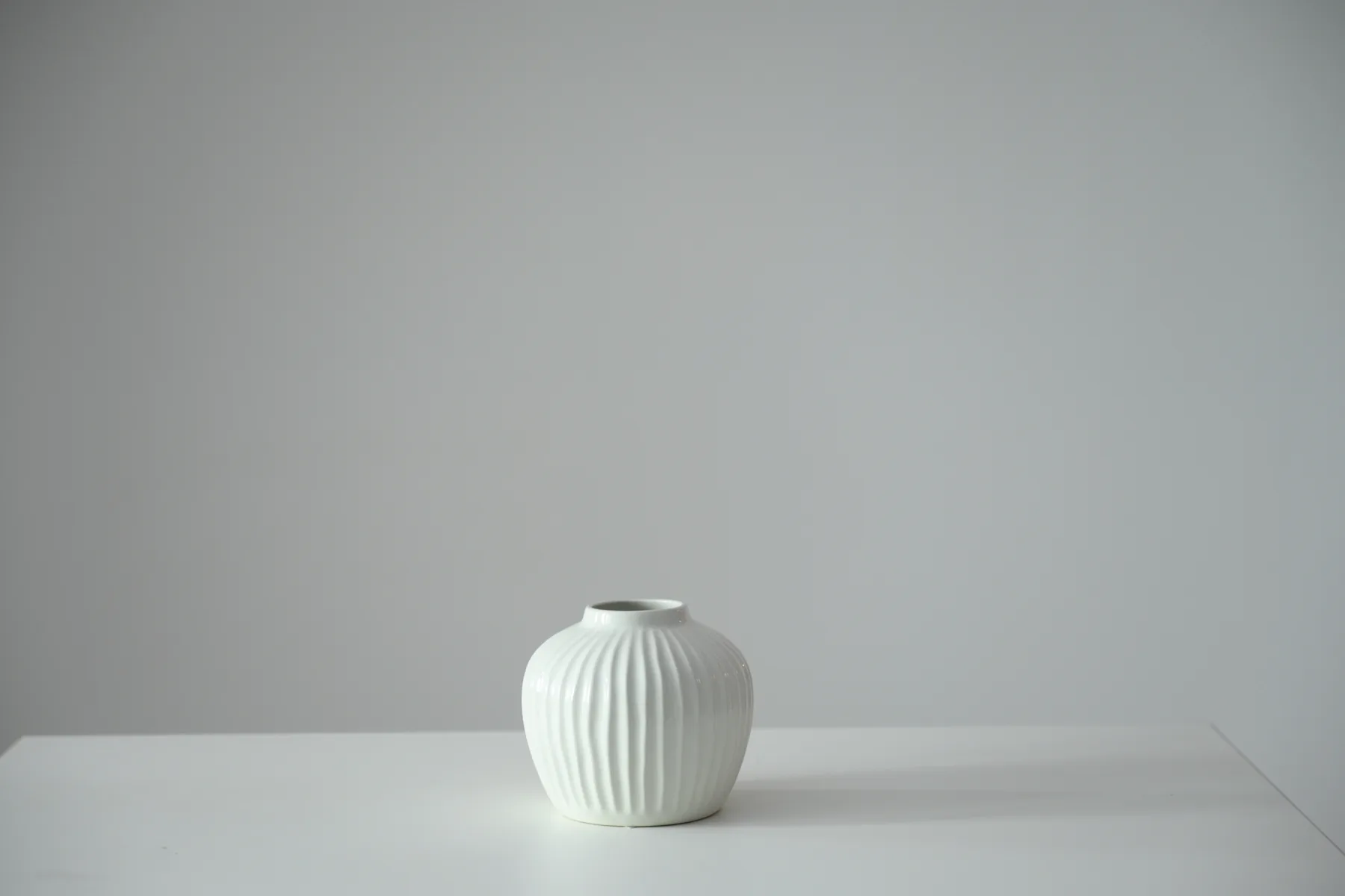 Small white fluted ceramic vase available as a studio prop